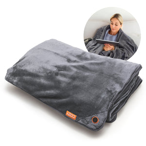A folded gray Cozy Wireless Rechargeable Snuggle Blanket Heated Throw with a power button and COZY tag; inset shows a woman using the heated blanket on a couch while reading a tablet.