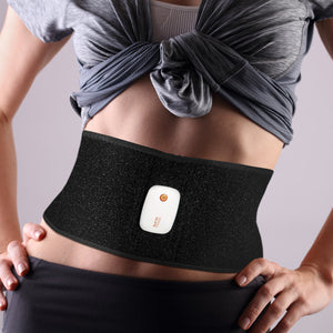 A person in a gray knotted top and dark pants is shown from chest to hips, wearing the Smart Fitness EMS Muscle Toning Belt with a small white device at the center to firm abs.