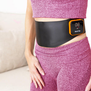 A person in a pink sports outfit wears the Ab & Back Muscle Strengthener with heat, featuring a small screen showing numbers, fastened around their waist.