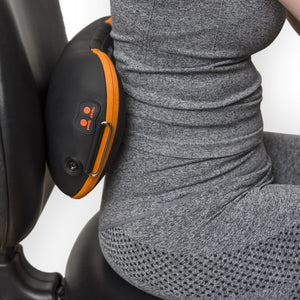 Wearing gray athletic wear, a person sits on a black chair using the Neck, Shoulder & Body Shiatsu Massager with orange accents and control buttons placed at their lower back.