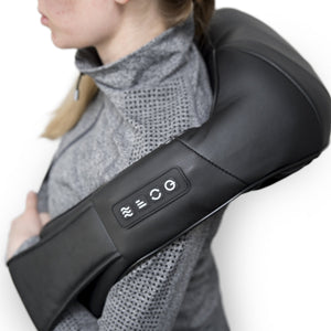 A person in a gray textured sweater uses the Neck & Shoulder Shiatsu Massager, a black device with visible control buttons, draped over their shoulders for deep kneading relief.