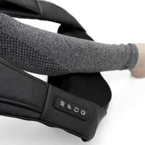 A person wearing a gray long-sleeve top uses the Neck & Shoulder Shiatsu Massager with control buttons and deep kneading action on their arm against a white background.