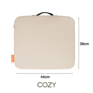 The COZY Cordless Heated Seat Pad - JORD is a rectangular beige portable cushion with a black handle, orange COZY tag, and measures 44 cm x 39 cm. COZY is printed below the seat.