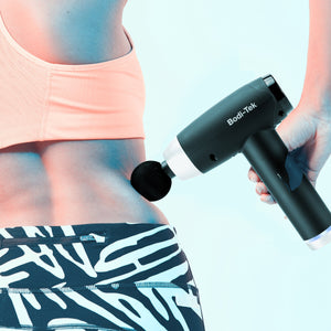 Wearing athletic wear, a person uses the Deep Tissue Sports Massage Gun on their lower back, holding it in their right hand against a light blue background.