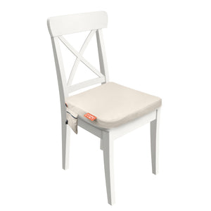 The COZY Cordless Heated Seat Pad - JORD is a white wooden chair with a light beige heated seat cushion, featuring a small side pocket with an orange 0C27 label—perfect for outdoor use.