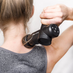 A person uses the Hot & Cold Deep Tissue Massager Gun on their neck and shoulder while wearing a gray athletic top. The devices display and controls are visible, aiding muscle recovery.