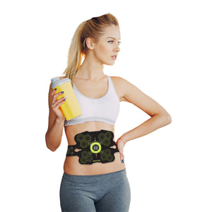 A woman in athletic wear holds a yellow sports drink and wears the black and green Abs and Oblique Trainer Pro on her midsection for targeted muscle stimulation, looking to the side against a white background.