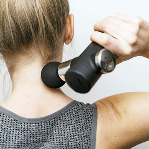 A person in a gray sleeveless top uses the Mini Deep Tissue Massage Gun on the back of their neck and upper shoulders, enjoying targeted relief with this portable, black percussive massager.