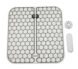 The Circulation Plus Boost & Revive Mat, a hexagon-patterned foot massage pad, is shown with a small round remote and a rectangular four-button control panel for portable leg exercise and muscle stimulation.