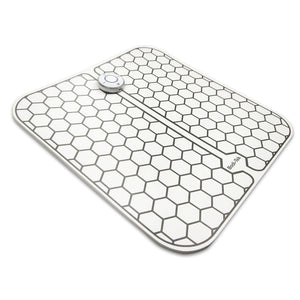 The Circulation Plus Boost & Revive Mat is a rectangular, flat device with a hexagonal grid, rounded corners, and a central circular button—perfect for portable leg exercise and improved circulation—shown on a white background.