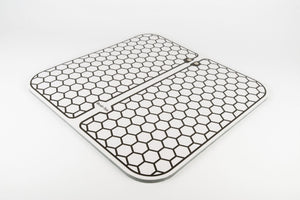 Two Circulation Plus Boost & Revive Mats, rectangular and white with black hexagonal honeycomb patterns and rounded corners, are placed side by side on a white background. One mat displays a small label with text.