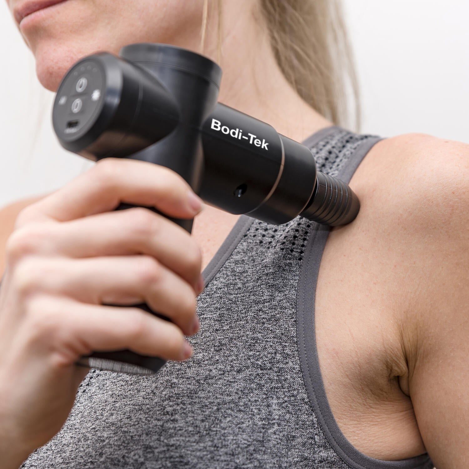 Women using massage gun on shoulder