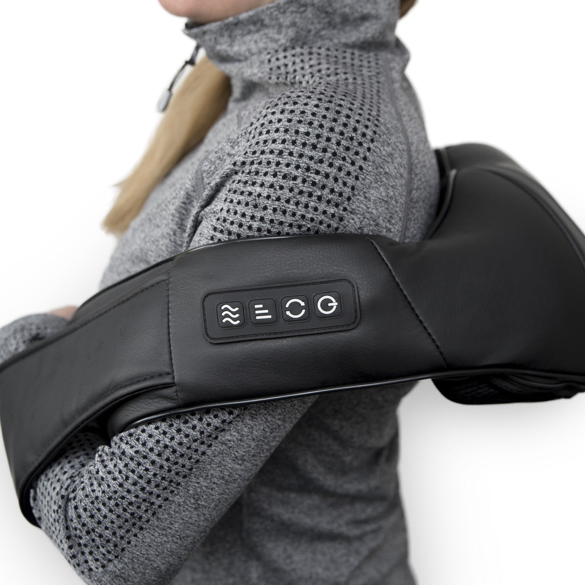 A person in a gray zip-up sweater uses the Neck & Shoulder Shiatsu Massager with side control buttons, resting it on their upper back and shoulders for deep kneading relief.