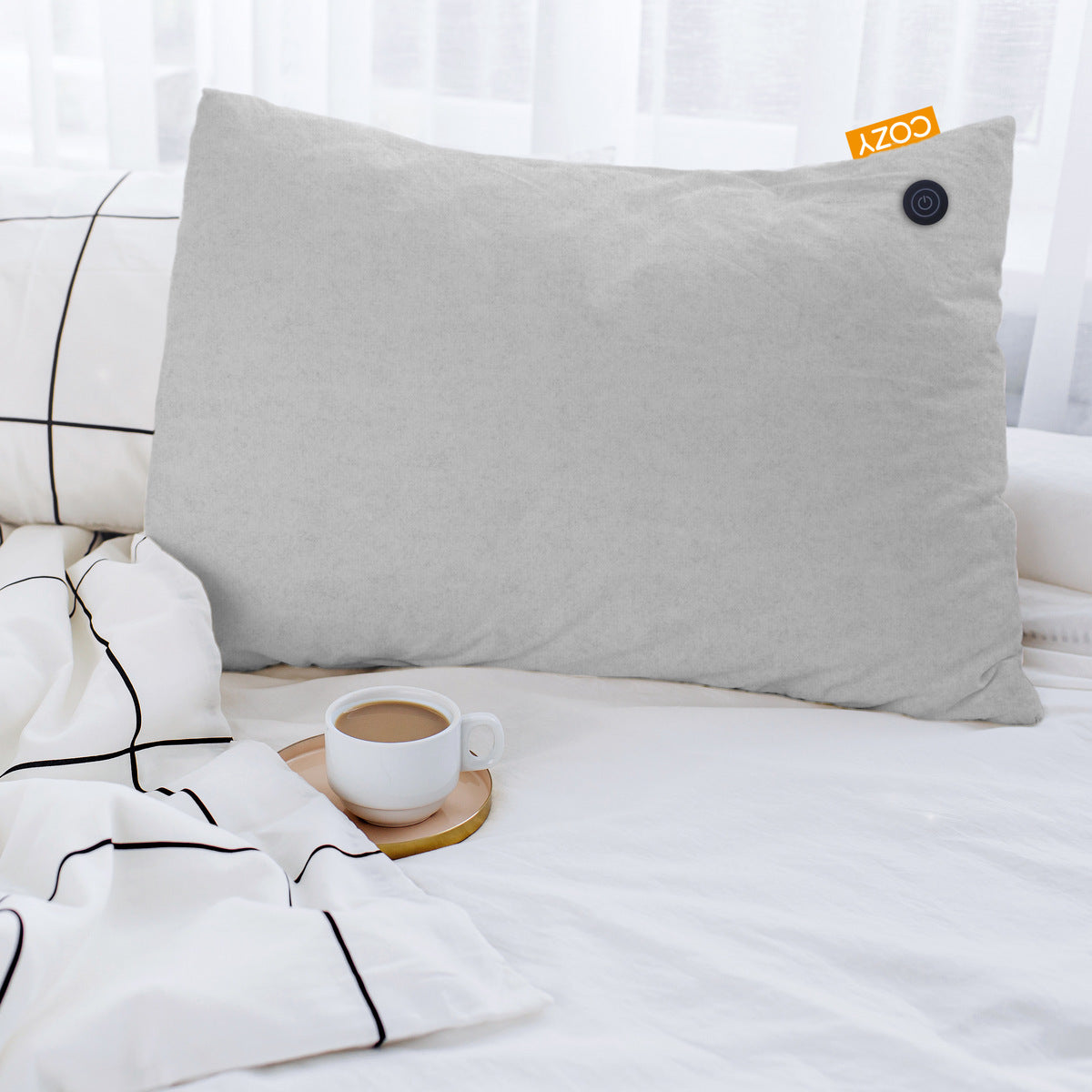 Heated grey cushion on white bed linen next to a hot cup of coffee.