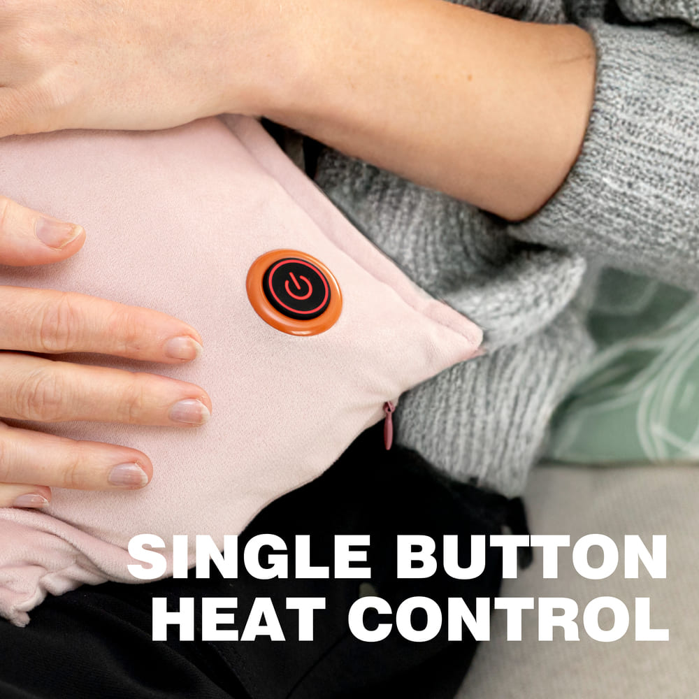 A person rests their hands on the pink Cozy UNA Rechargeable Hot Water Bottle, featuring a single large power button for simple heat control. Text on the image reads, SINGLE BUTTON HEAT CONTROL.