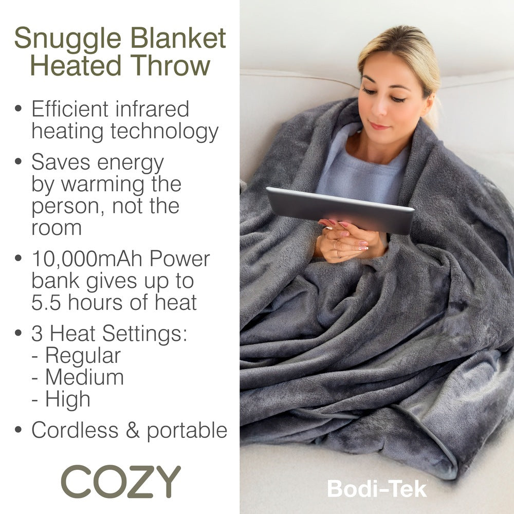 A woman sits on a couch, wrapped in the Cozy Wireless Rechargeable Snuggle Blanket Heated Throw while using a tablet. Text highlights its infrared heating, built-in power bank, and three adjustable heat settings.