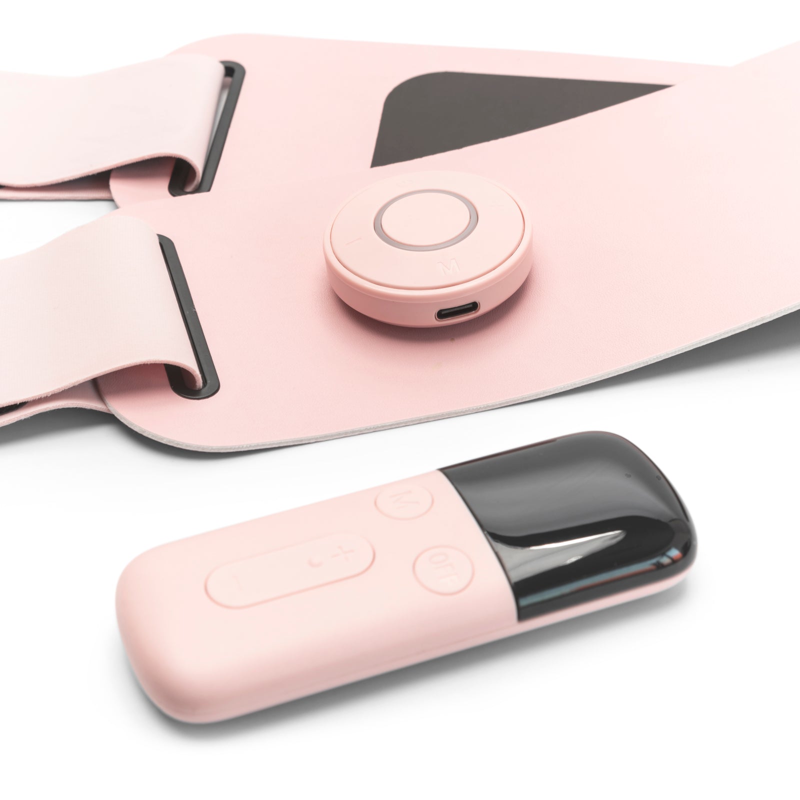 A close-up of the Ab, Tone & Shape EMS abdominal belt with a round button and matching remote, both on a white surface. This wearable device features black accents for muscle stimulation and ab toning.