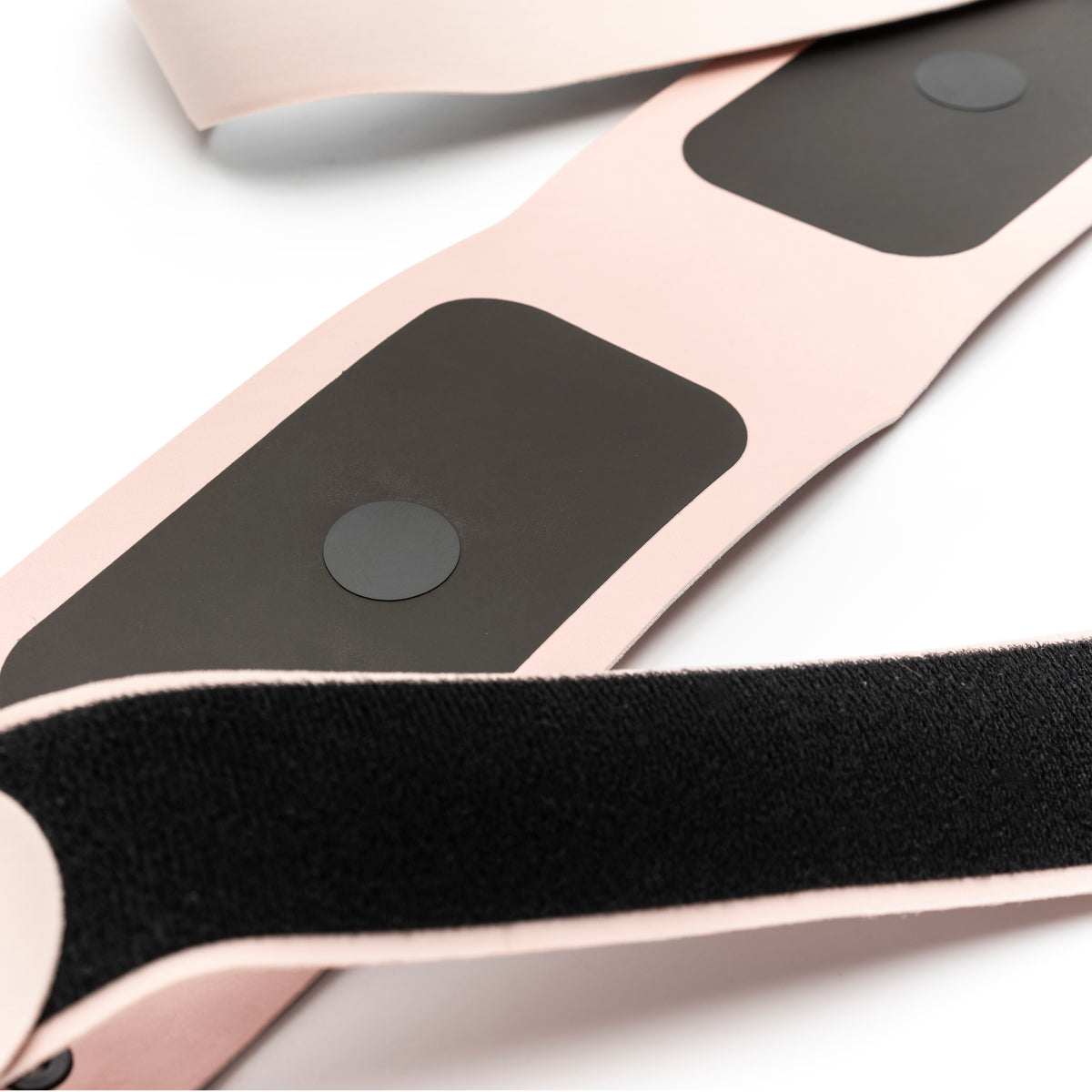 Close-up of a light pink strap with large black velcro and adhesive pads from the Ab, Tone & Shape EMS abdominal belt, set against a white background.